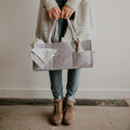 Supplier reference lifestyle photo of an adult carrying a grey felt nursery caddy. Third-party branding visible; exact LEONO sample pending.
